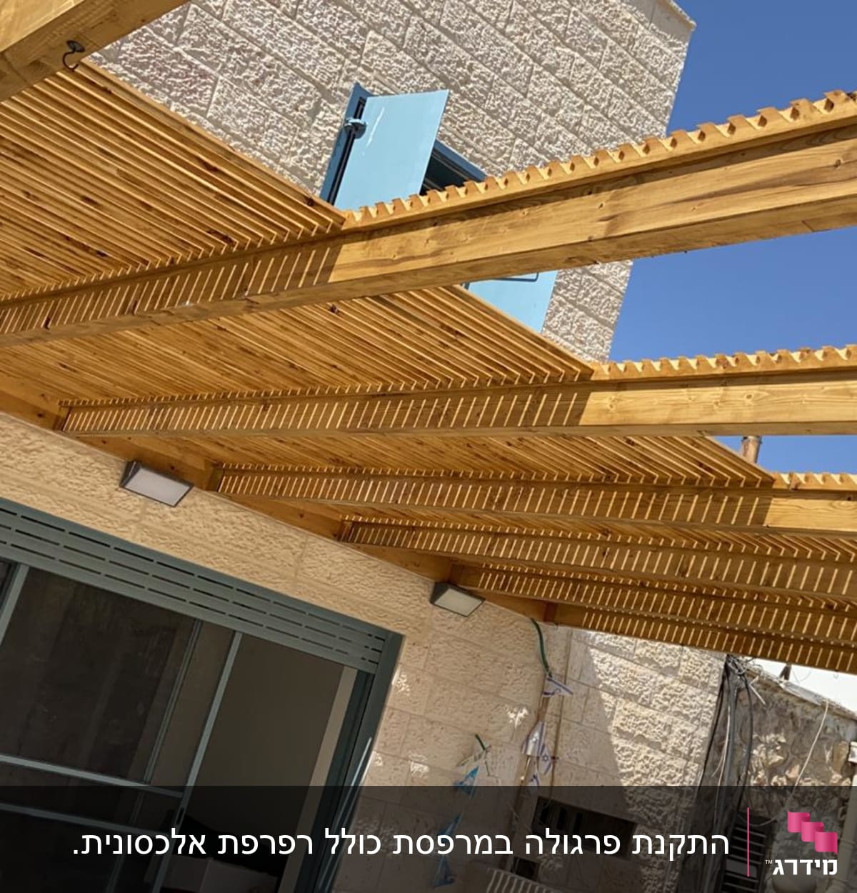 פרגולה מעץ עם קורות עץ על קיר אבן